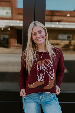 Model wearing Maroon Sweater with Cowboy boots design.