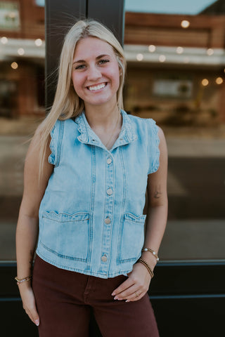 Model wearing denim vest with scalloped edge detailing.